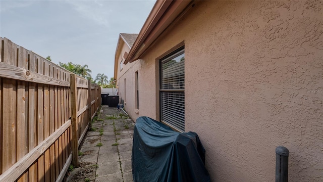 view of side of home with stucco siding and fence