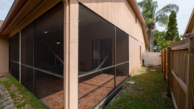 view of property exterior featuring fence, a sunroom, and stucco siding