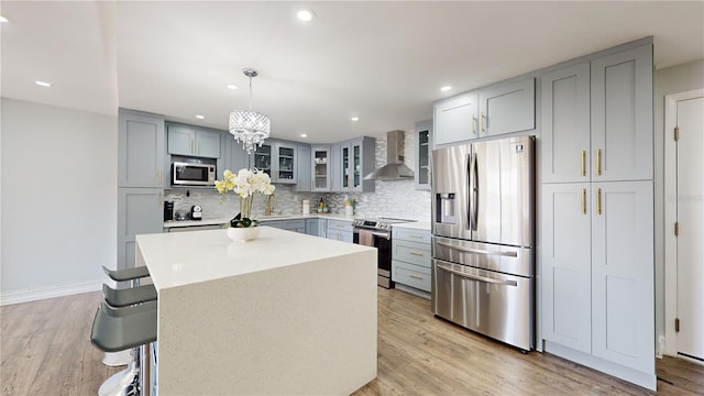 400 Island Way Unit 210, Clearwater Beach, FL 33767 - kitchen featuring stainless steel appliances, wall chimney range hood, gray cabinetry, backsplash, and glass insert cabinets