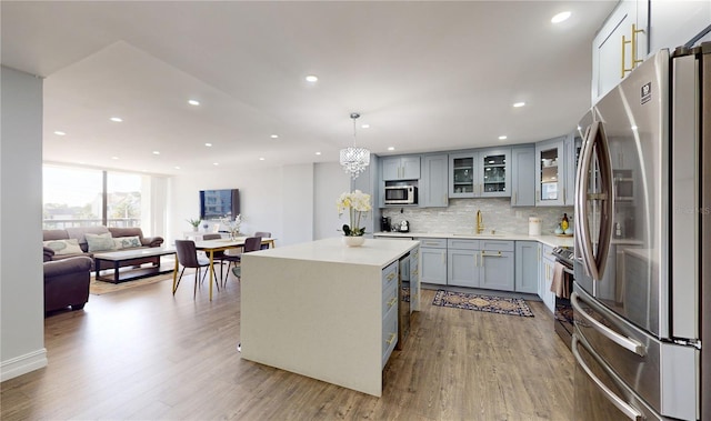 400 Island Way Unit 210, Clearwater Beach, FL 33767 - kitchen featuring stainless steel appliances, wood finished floors, recessed lighting, decorative backsplash, and light countertops