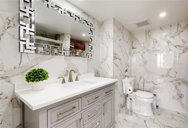 400 Island Way Unit 210, Clearwater Beach, FL 33767 - bathroom featuring tile walls, toilet, vanity, marble tiled floors, and stone wall