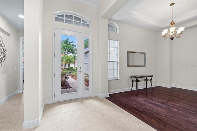 entryway with baseboards, an inviting chandelier, crown molding, and wood finished floors