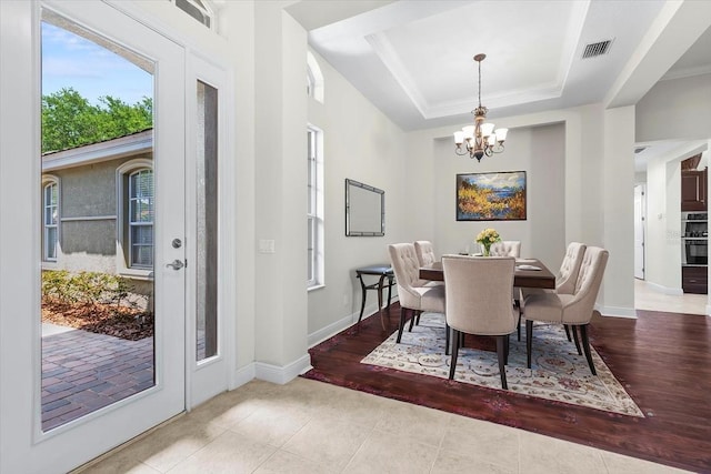 dining area with baseboards, an inviting chandelier, visible vents, tile patterned flooring, and a raised ceiling