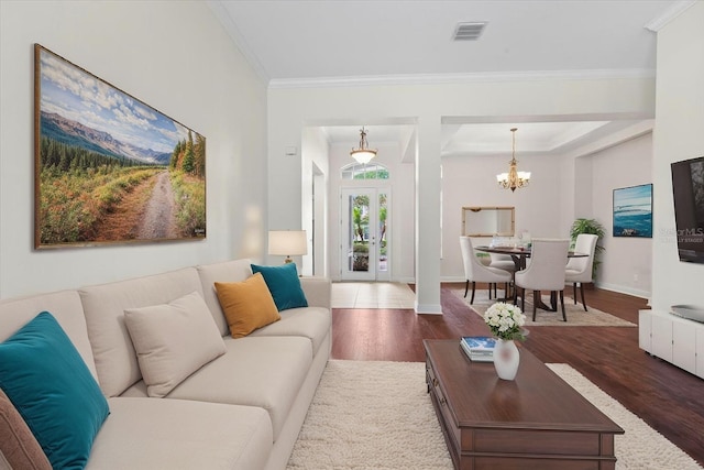 living area with baseboards, visible vents, a chandelier, crown molding, and wood finished floors
