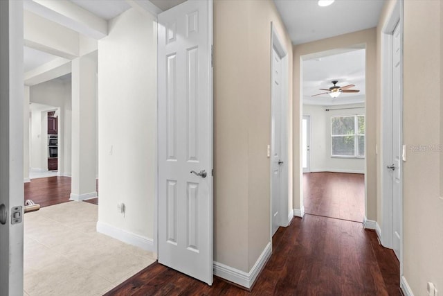 corridor with baseboards and wood finished floors