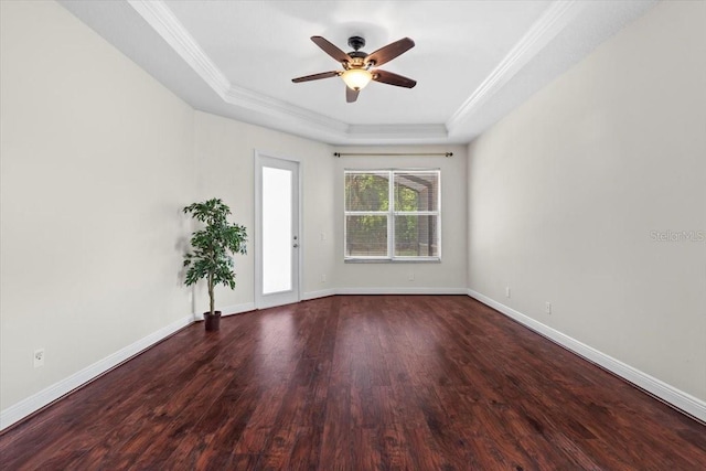 spare room with a tray ceiling, wood finished floors, ceiling fan, and ornamental molding