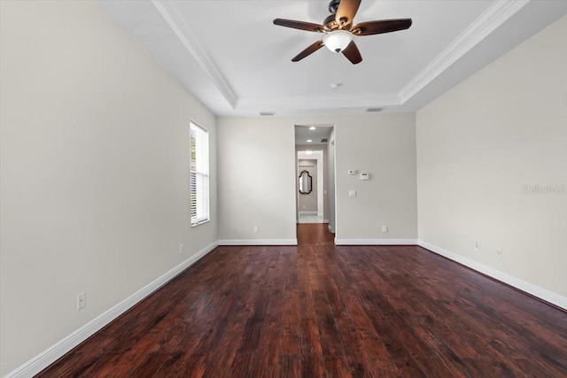 spare room featuring wood finished floors, ceiling fan, crown molding, a tray ceiling, and baseboards