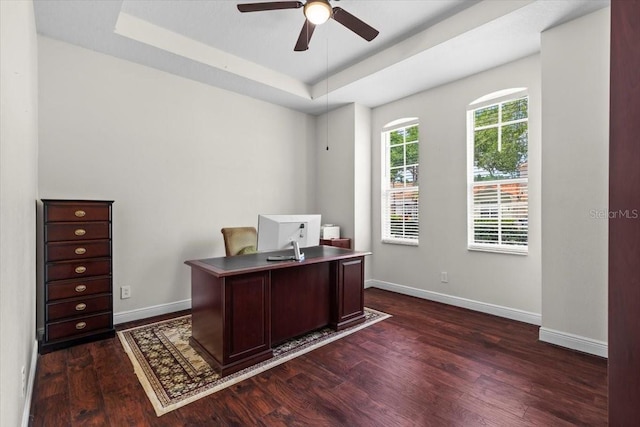 home office featuring baseboards, dark wood finished floors, a tray ceiling, and ceiling fan