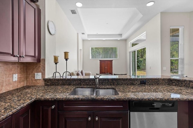 kitchen featuring stainless steel dishwasher, visible vents, a sink, a raised ceiling, and tasteful backsplash