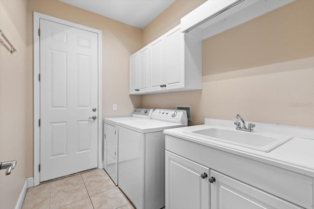 laundry area with a sink, cabinet space, washer and clothes dryer, baseboards, and light tile patterned flooring