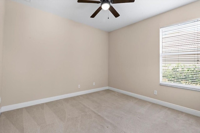 spare room featuring light colored carpet, baseboards, and ceiling fan