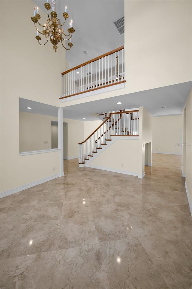 unfurnished living room featuring visible vents, a towering ceiling, baseboards, and stairs