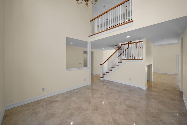 unfurnished living room with baseboards, a towering ceiling, a notable chandelier, and stairway