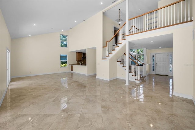 unfurnished living room featuring baseboards, a high ceiling, marble finish floor, and stairway