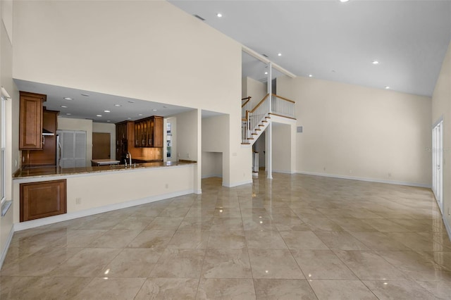 unfurnished living room featuring a sink, baseboards, marble finish floor, stairway, and high vaulted ceiling