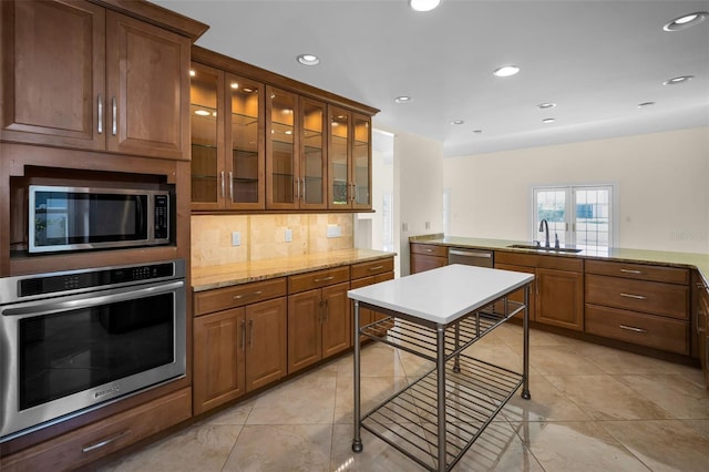 kitchen featuring recessed lighting, backsplash, a sink, glass insert cabinets, and appliances with stainless steel finishes