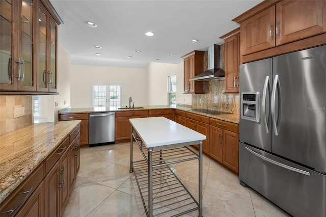 kitchen with wall chimney range hood, tasteful backsplash, stainless steel appliances, and a sink
