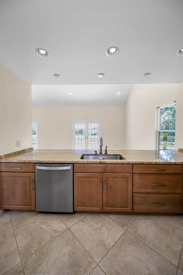 kitchen featuring dishwasher, a healthy amount of sunlight, brown cabinetry, and a sink