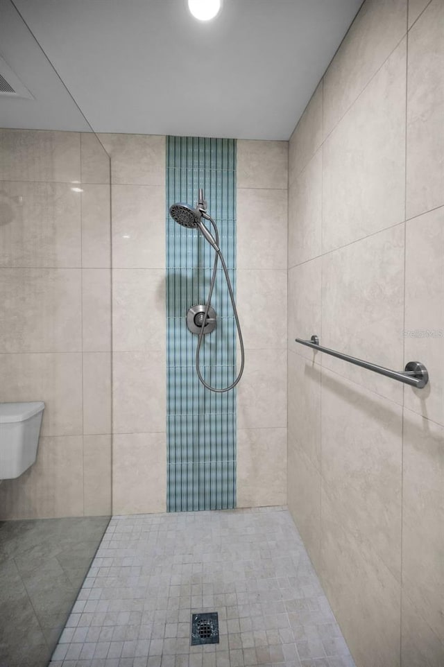 bathroom with a tile shower and toilet