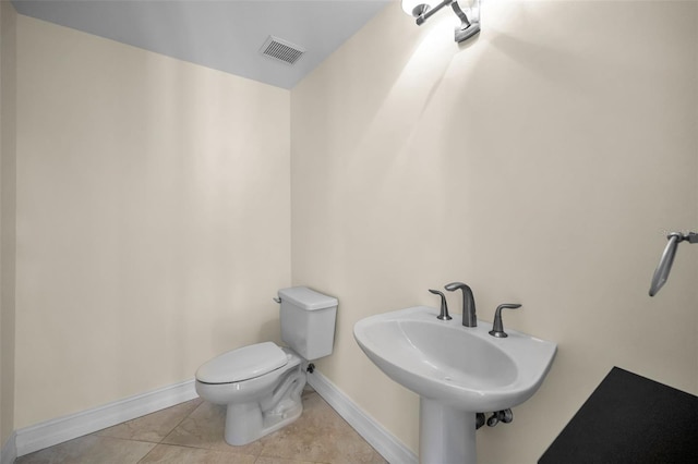 bathroom with a sink, toilet, baseboards, visible vents, and tile patterned flooring