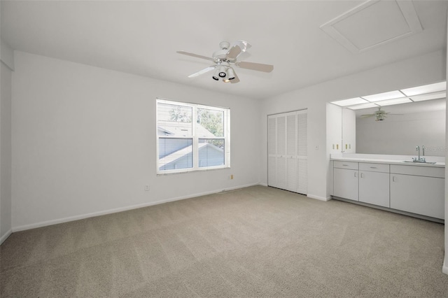 interior space featuring light carpet, baseboards, and a sink
