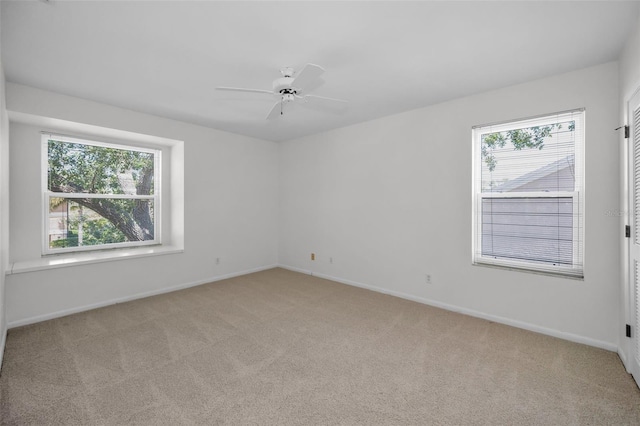 carpeted spare room featuring ceiling fan and baseboards
