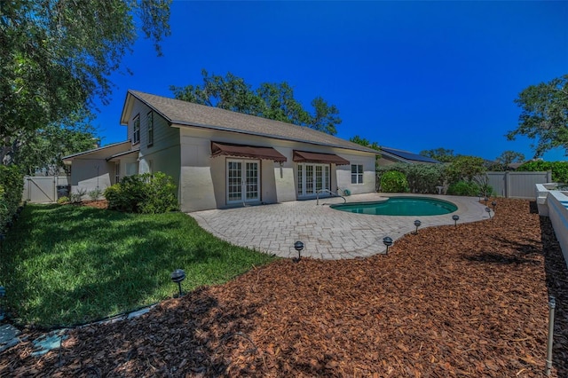 back of house with a fenced in pool, a fenced backyard, french doors, a patio, and a lawn