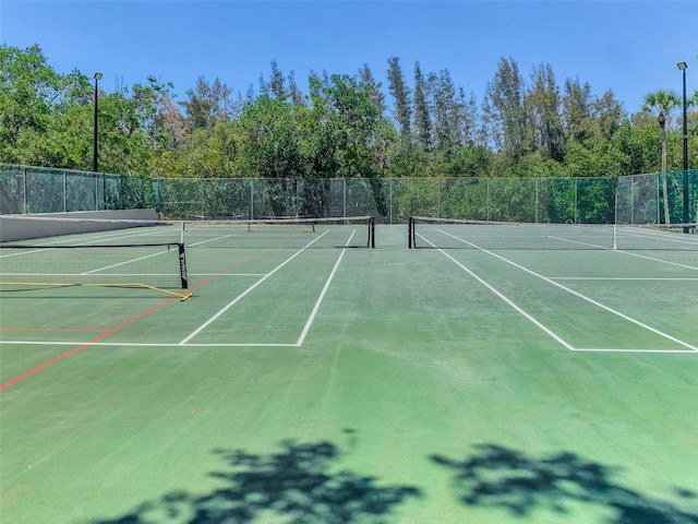 view of tennis court featuring community basketball court and fence