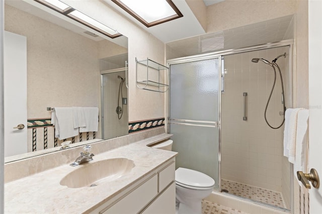 full bath with vanity, a stall shower, and toilet