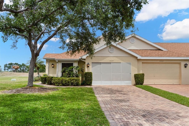 single story home with a front lawn, decorative driveway, an attached garage, and stucco siding