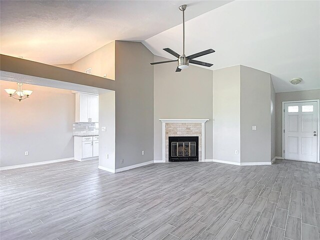 1530 High Knoll Dr, Brandon, FL 33511 - unfurnished living room with light wood-style flooring, a ceiling fan, a chandelier, a glass covered fireplace, and high vaulted ceiling