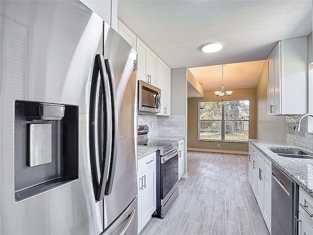 1530 High Knoll Dr, Brandon, FL 33511 - kitchen featuring stainless steel appliances, a chandelier, backsplash, white cabinetry, and a textured ceiling