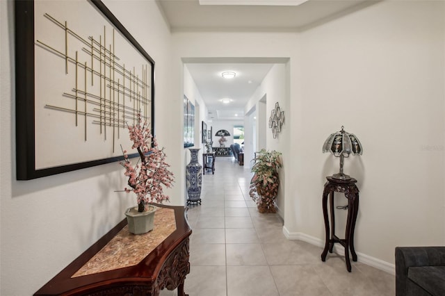 corridor featuring baseboards and light tile patterned flooring
