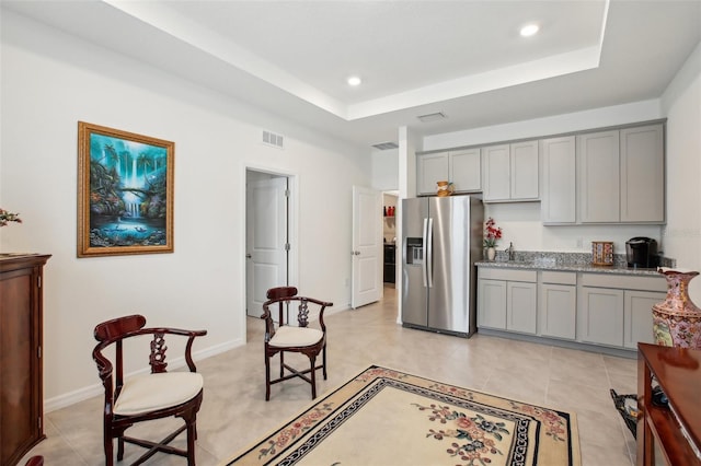 living area featuring recessed lighting, a raised ceiling, and visible vents