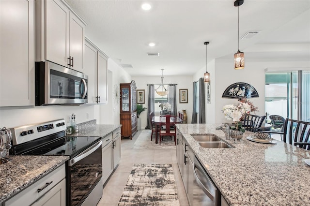 kitchen with visible vents, light tile patterned floors, a sink, light stone countertops, and appliances with stainless steel finishes