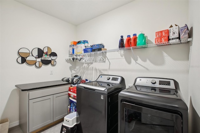 laundry area with separate washer and dryer, baseboards, and cabinet space