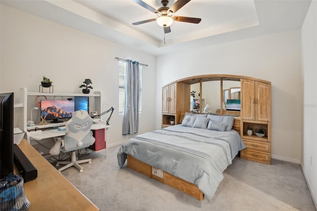 bedroom with light carpet, a ceiling fan, baseboards, and a raised ceiling