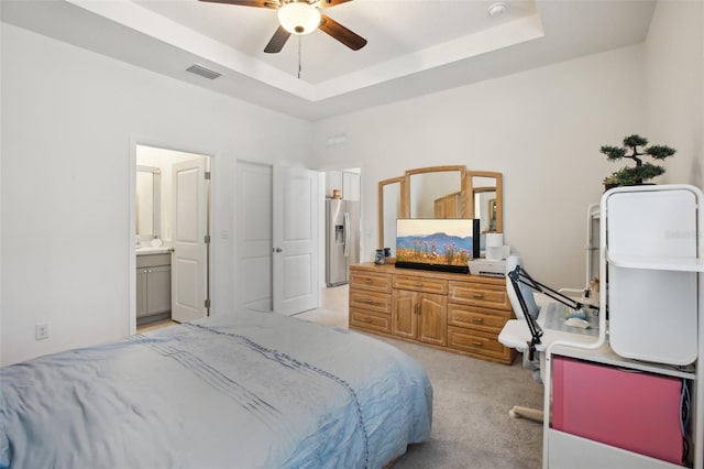 bedroom with visible vents, light carpet, a tray ceiling, and stainless steel fridge with ice dispenser
