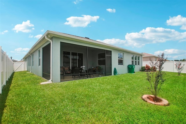 rear view of property with a lawn, a fenced backyard, a sunroom, and stucco siding