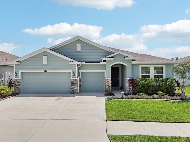 view of front of home featuring driveway, stone siding, a garage, a front yard, and stucco siding