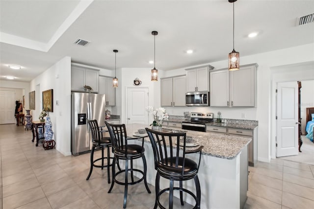 7323 Steer Blade Dr, Zephyrhills, FL 33541 - kitchen with stainless steel appliances, gray cabinets, a breakfast bar, light stone countertops, and recessed lighting
