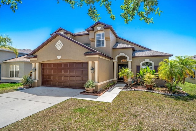 mediterranean / spanish-style house featuring stucco siding, an attached garage, driveway, and a front yard