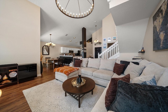 living area featuring wood finished floors, an inviting chandelier, stairway, and high vaulted ceiling
