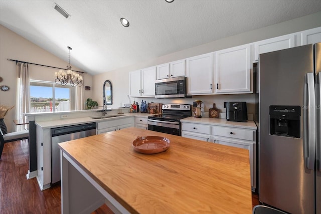 kitchen featuring stainless steel appliances, an inviting chandelier, vaulted ceiling, a sink, and a peninsula