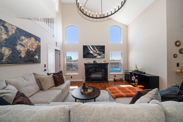 living room featuring wood finished floors, a wealth of natural light, high vaulted ceiling, and a notable chandelier