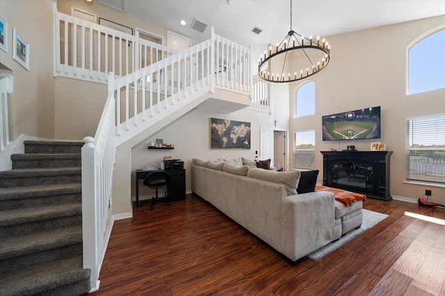 living room with dark wood finished floors, baseboards, an inviting chandelier, a high ceiling, and stairs