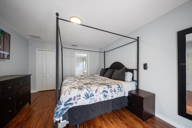 bedroom with baseboards, wood finished floors, visible vents, and a closet