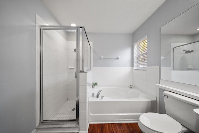 full bathroom with wood finished floors, a garden tub, toilet, and a stall shower