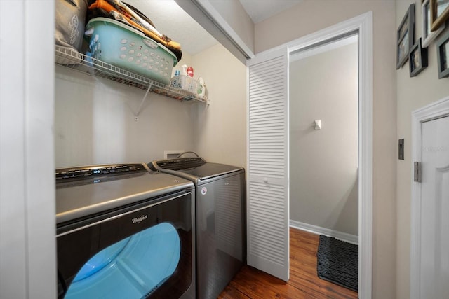 clothes washing area with dark wood-type flooring, washing machine and clothes dryer, baseboards, and laundry area