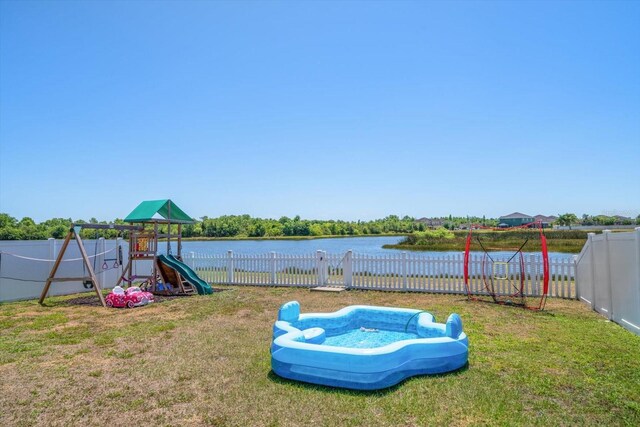 view of yard with a fenced backyard, a playground, and a water view